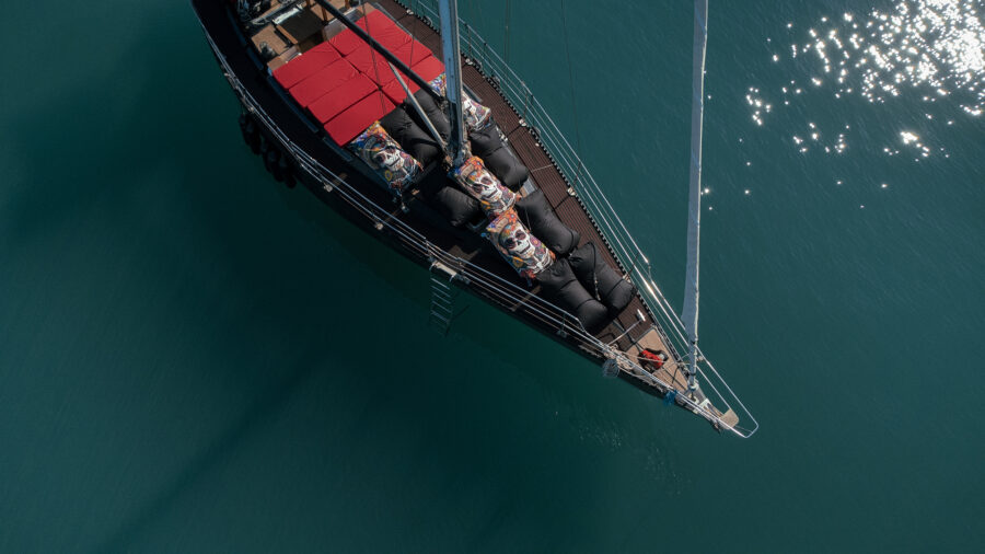 Relaxing on yacht deck with sunbeds and bean bags in Mykonos, enjoying the sea breeze and turquoise water views.